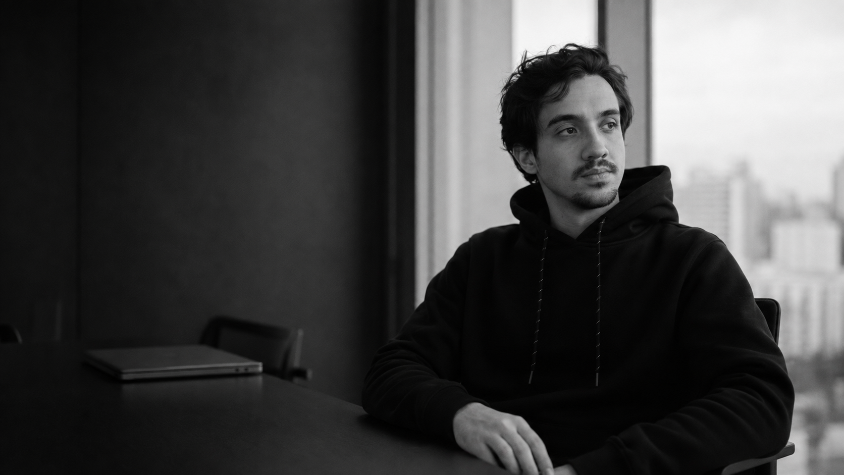 Amaral sentado à mesa, em preto e branco, olhando pela janela